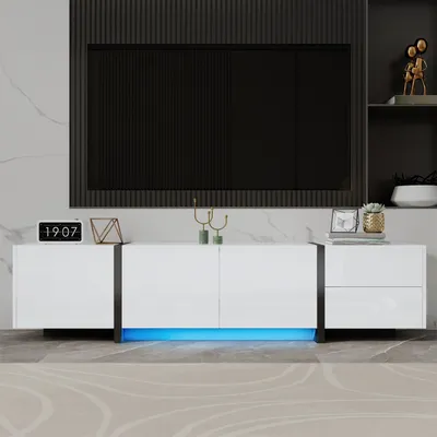 A modern white TV cabinet with LED lighting and a large black television mounted above it.