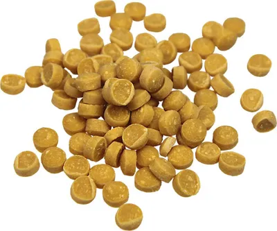 A pile of small, round, yellow-brown dog treats on a white background.