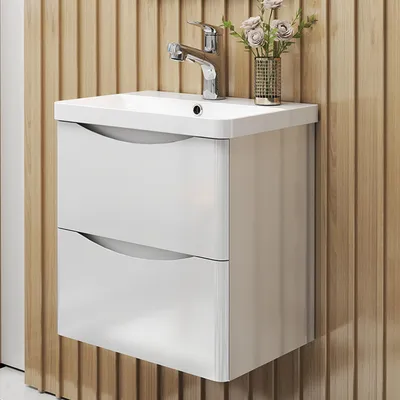 A white bathroom vanity with two drawers and a chrome faucet is mounted on a slatted wooden wall.