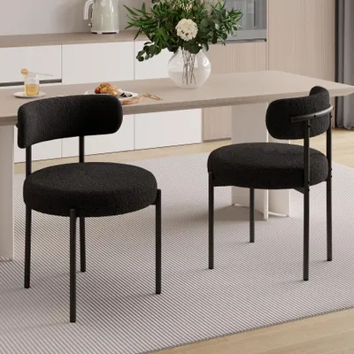 Two black chairs are placed in a dining room setting next to a table.