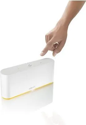 A hand is shown pressing a button on a white smart home hub with a yellow accent.