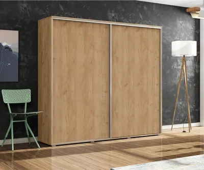 A spacious wardrobe with sliding doors is shown in a room with a dark textured wall, a green chair, and a floor lamp.