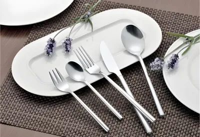 A set of cutlery is arranged on a white serving dish with lavender sprigs.