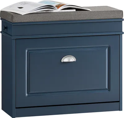 A blue shoe cabinet with a gray seat cushion on top, with a book placed on the cushion.
