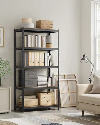 A storage shelf unit filled with books and boxes in a room with a sofa and a window.