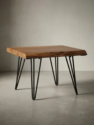 Freigestellter Design Couchtisch aus Massivholz in der Frontansicht. Der kompakte Holztisch zeigt seine natürliche Baumkante und grazile, schwarze Haarnadelbeine aus Metall._#sku_SAFWL5.204#