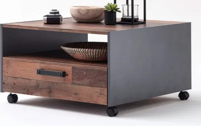 A modern coffee table with a drawer and open shelf, featuring mixed materials of wood and gray metal, set on casters.