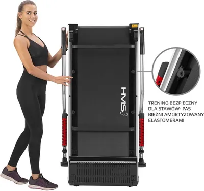 A woman stands next to a folded treadmill.