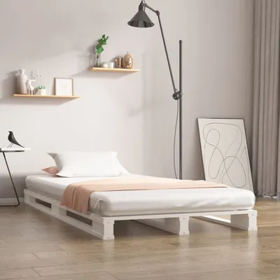 A bedroom setting with a bed frame, mattress, pillow, and blanket.