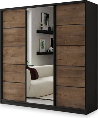 A three-door sliding wardrobe with a mirror in the center, reflecting a sofa and shelves with decor.
