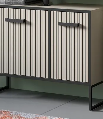 A close-up view of a modern cabinet with two doors, featuring a ribbed texture and black handles, set against a green wall and a gray floor.