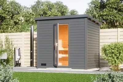 An outdoor sauna with an open door, showing the interior, set in a garden with a fence and trees in the background.
