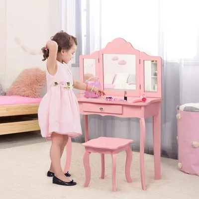 A young girl is playing with a pink toy vanity set in a child's room.