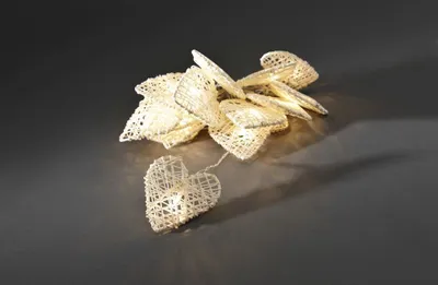 A string of heart-shaped LED lights made of woven branches, displayed on a dark reflective surface.