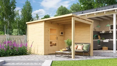 A wooden sauna house with an attached covered outdoor kitchen area, set in a garden with flowers and patio.