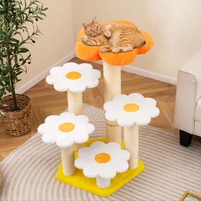 A cat is resting on a multi-tiered cat tree designed to look like flowers, placed in a room with a plant and furniture.