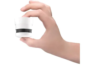 A hand holds a small white smoke detector.