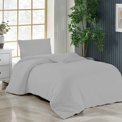 A neatly made bed with gray bedding in a room with a large window and a plant.