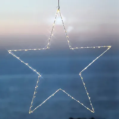 A star-shaped light decoration hanging against a blurred sky background.