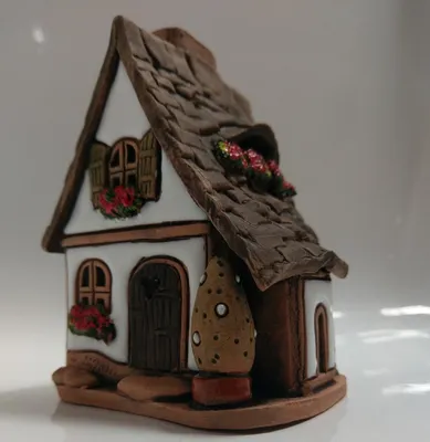 Ein kleines malerisches Hauses mit braunen Ziegeldach, weißen Wänden und detaillierten Fensterläden.