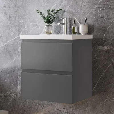 A modern bathroom vanity with two drawers against a marble-tiled wall.