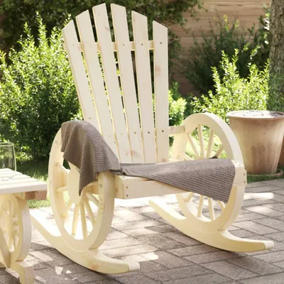 A wooden Adirondack rocking chair with wheel accents sits on a brick patio, surrounded by greenery.