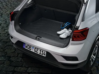 The trunk of a white car with a black cargo liner, a blue helmet, and white cycling shoes.