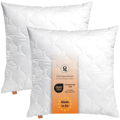 Two white pillows are shown, one slightly behind the other, with a product tag attached to the front pillow.