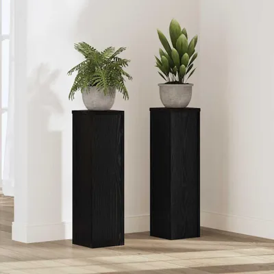 Two black plant stands with plants on top, placed in a room.
