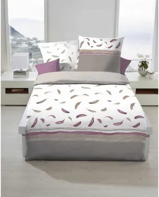 A neatly made bed with a duvet cover and pillows, set against a window with a view of a coastal town.