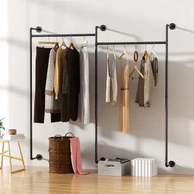 Two industrial-style pipe clothing racks mounted on a white wall, displaying various garments and accessories.