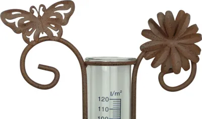 A close-up of a decorative rain gauge with a butterfly and flower motif.