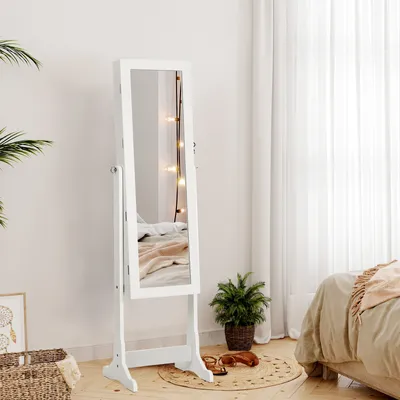 A white jewelry cabinet with a mirror stands in a bedroom next to a bed and a plant.