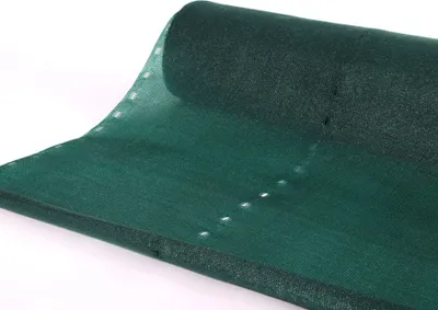 A roll of dark green shade netting is laid out on a white surface.