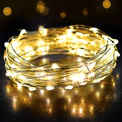 A coiled string of warm white LED lights on a dark, reflective surface.