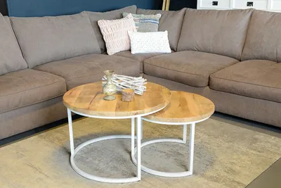 A sectional sofa with two nesting coffee tables in front of it, placed on a rug.