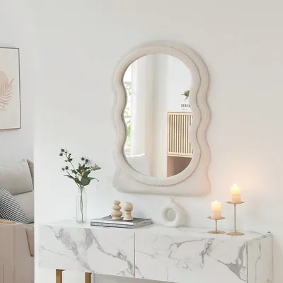 A fluffy-edged mirror is displayed above a marble-patterned console table with decorative items.