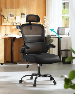 A black ergonomic office chair with a mesh back is shown in a home office setting.