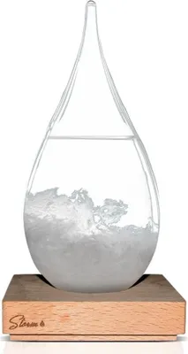 A clear glass storm glass barometer with a wooden base.