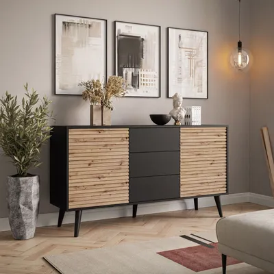 A modern living room with a sideboard, artwork, and a plant.