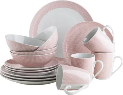 A collection of pink and white porcelain dinnerware, including plates, bowls, and mugs, arranged in a studio setting.