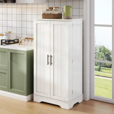 A white kitchen cabinet with two doors stands next to a window in a kitchen setting.