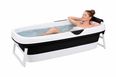 A woman is relaxing in a portable bathtub filled with water.