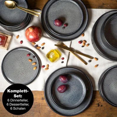 A table setting with plates, cutlery, fruit, and a small dish of oil.
