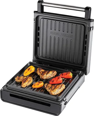 An open George Foreman grill with chicken and peppers cooking on the grates.