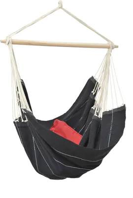 A hammock chair suspended from a wooden bar and rope, with a red cushion inside.