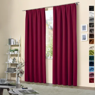 Two burgundy curtains hanging in a room, with a shelf unit and a window in the background.