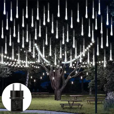 Outdoor scene at night with decorative lights strung on a tree and a power adapter shown in a circle.
