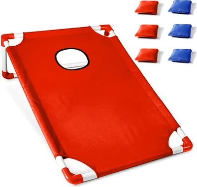 A red cornhole board with white frame and a hole in the center, with red and blue bean bags in the background.