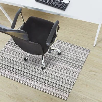 An office chair on a striped mat in front of a desk.